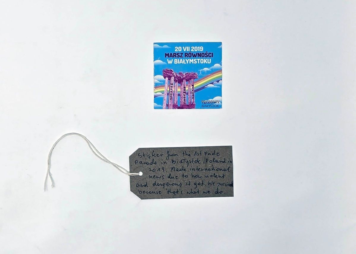 A square sticker which has a blue background and a rainbow and clouds. There is text on it.