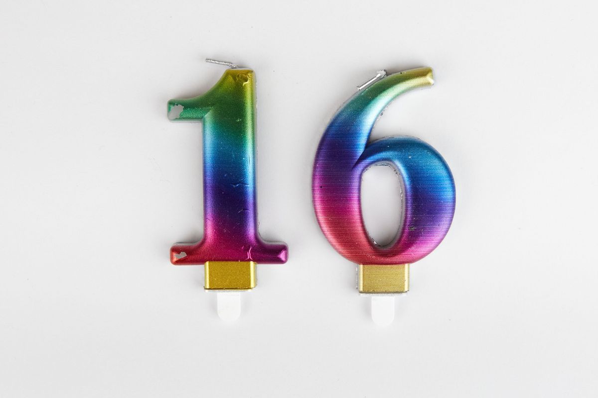 Two candles, one '1' and one '6' to spell '16'. The candles are rainbow coloured.