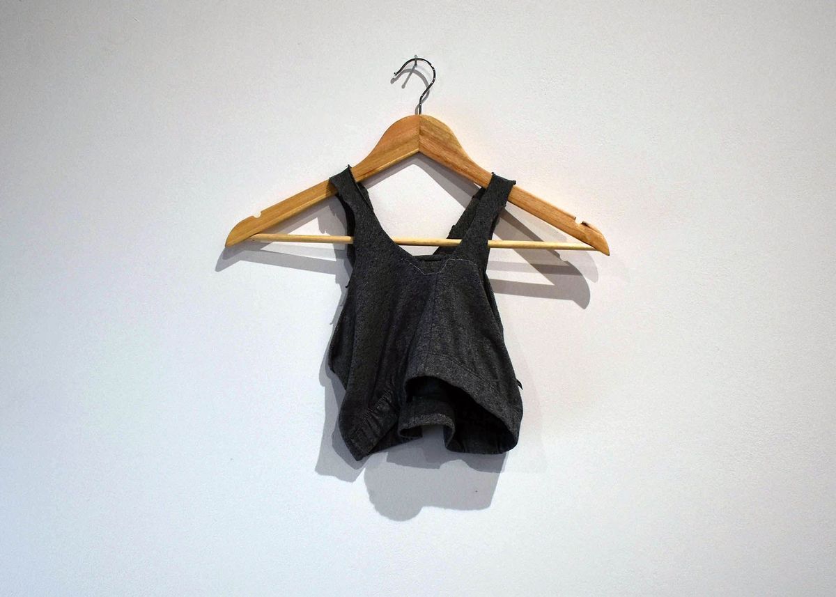 A handmade dark grey binder, made out of a pair of leggings, on a wooden hanger.