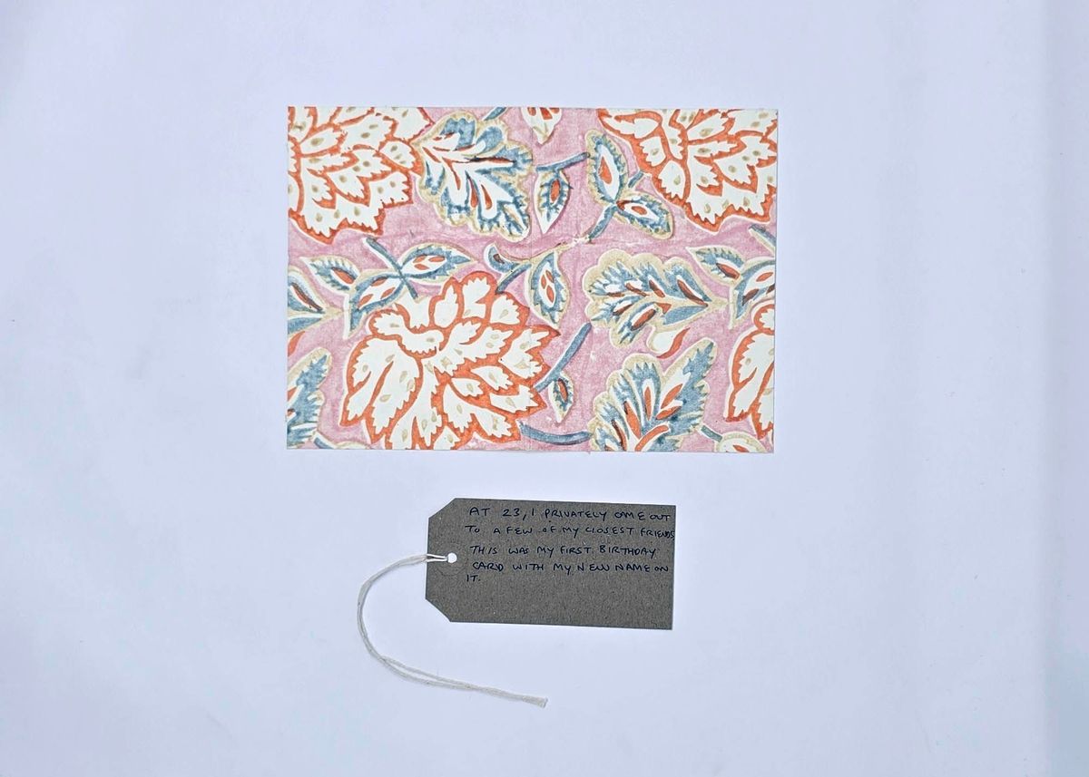 The image shows a floral pattern on pink, accompanied by a handwritten note on a tag.