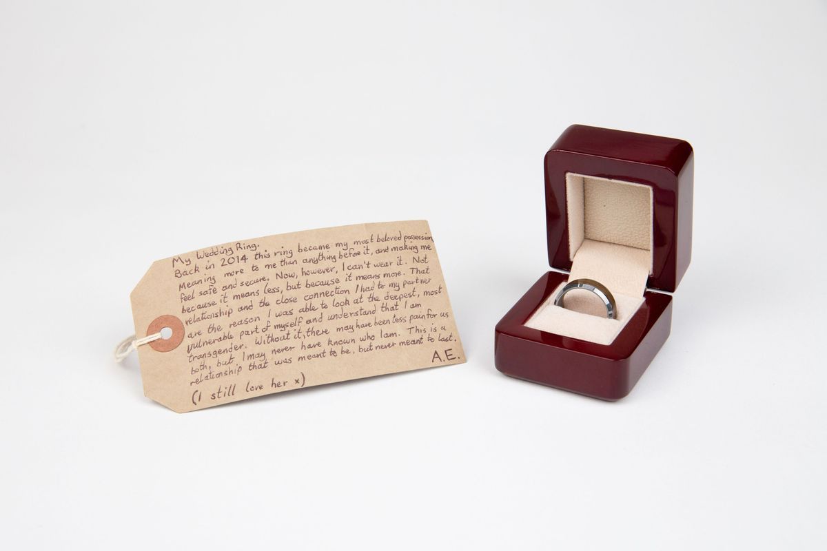 Dark red box with soft grey lining. Inside is a metal ring with a wood circle along the middle of the outside edge.