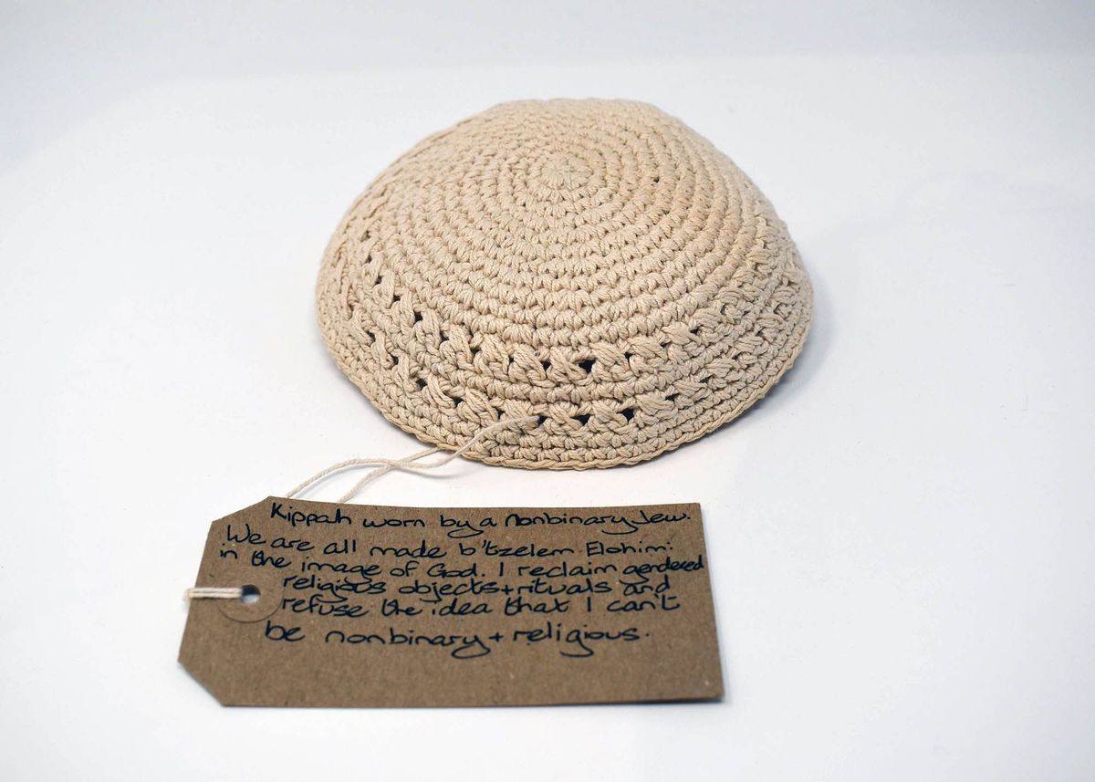 A beige crocheted kippah sits near a handwritten note discussing nonbinary and religious identity.