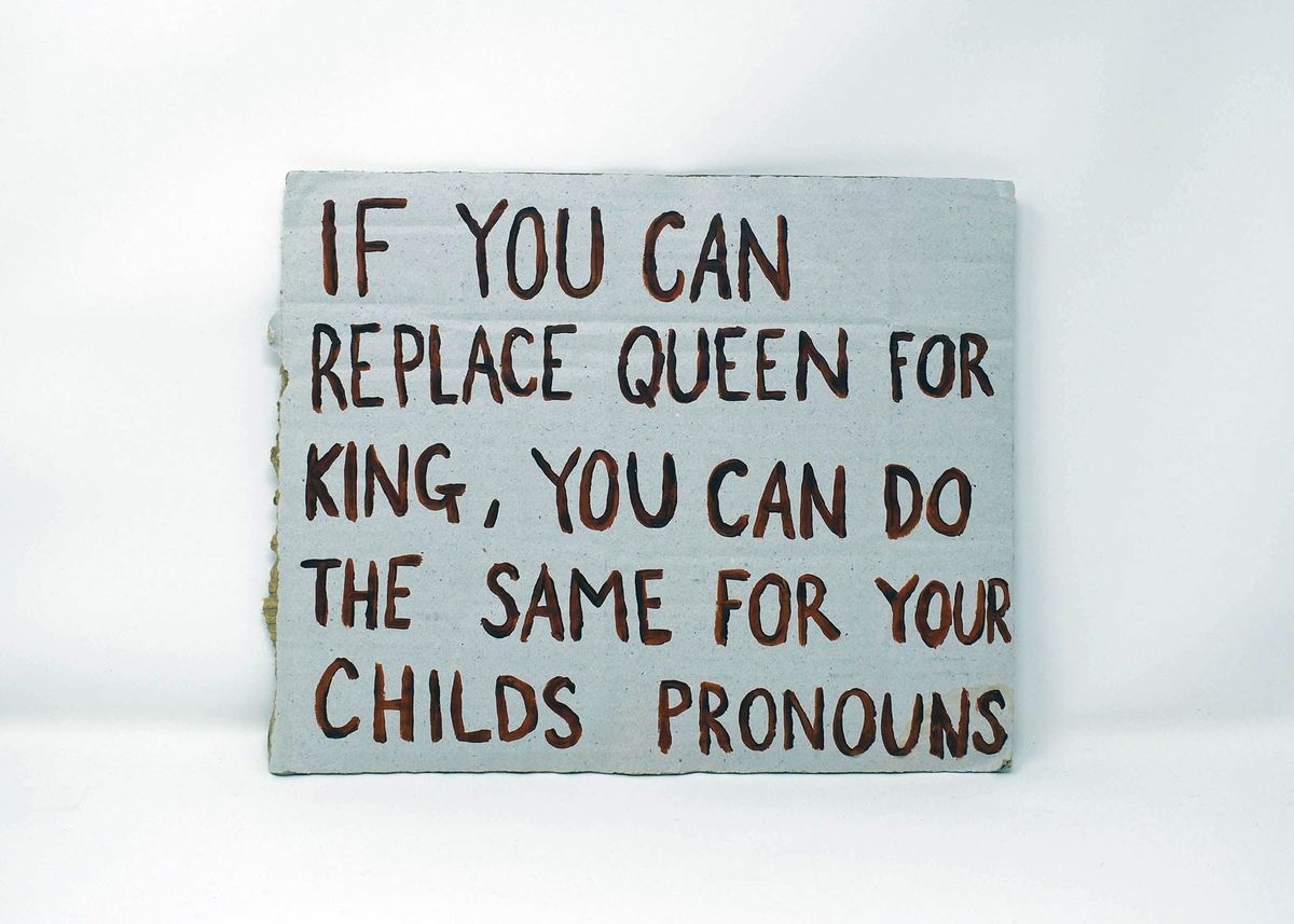 A placard which is a light blue and has writing painted on it saying 'If you can replace queen for king, you can do the same for your childs pronouns'.