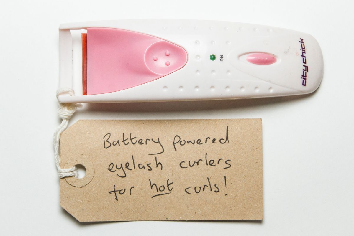 Handheld battery operated eyelash curler. It is white with pink buttons and the brand "citychick" written in black on the bottom of the handle.