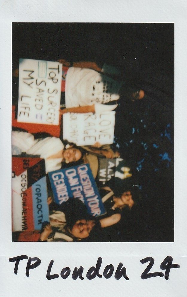 A group of people holds various protest signs promoting body autonomy and gender choice.
