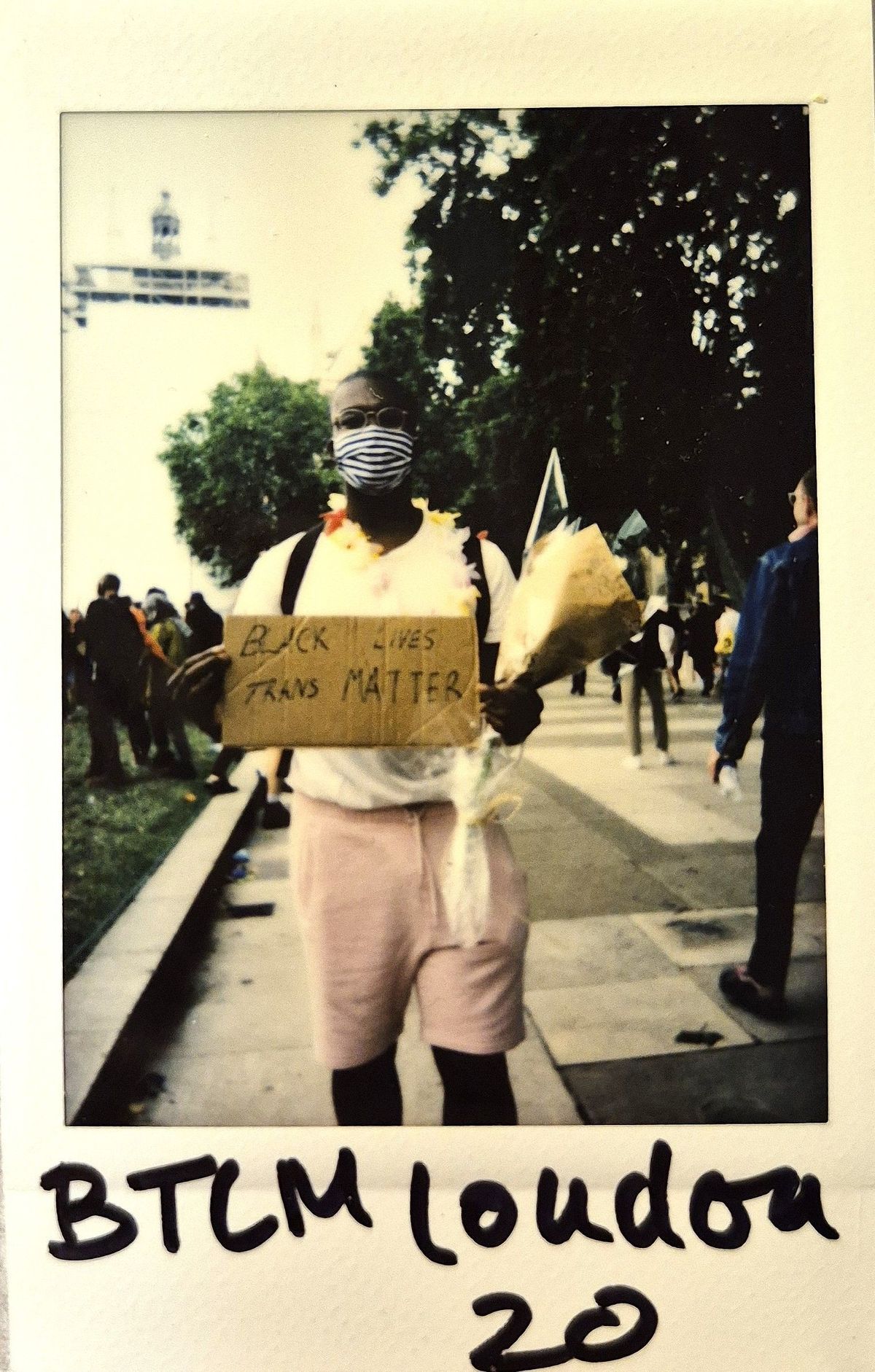 A person holds a "Black Trans Lives Matter" sign.