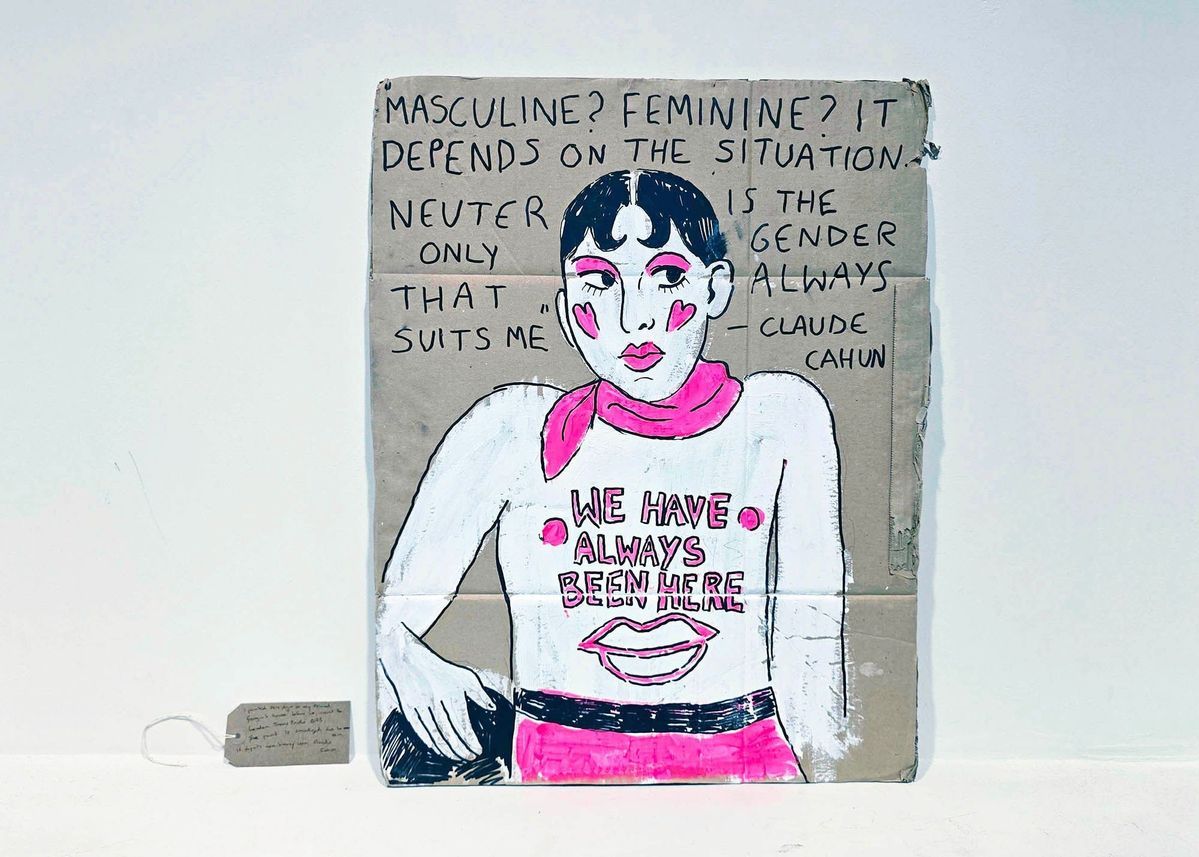 A brown cardboard placard painted with the image of a topless person with black hair, a pink scarf and pink trousers. The text "WE HAVE ALWAYS BEEN HERE" is written o n their chest. Above the painting is a quote about gender expression from Claude Cahun. With a brown, handwritten luggage tag.
