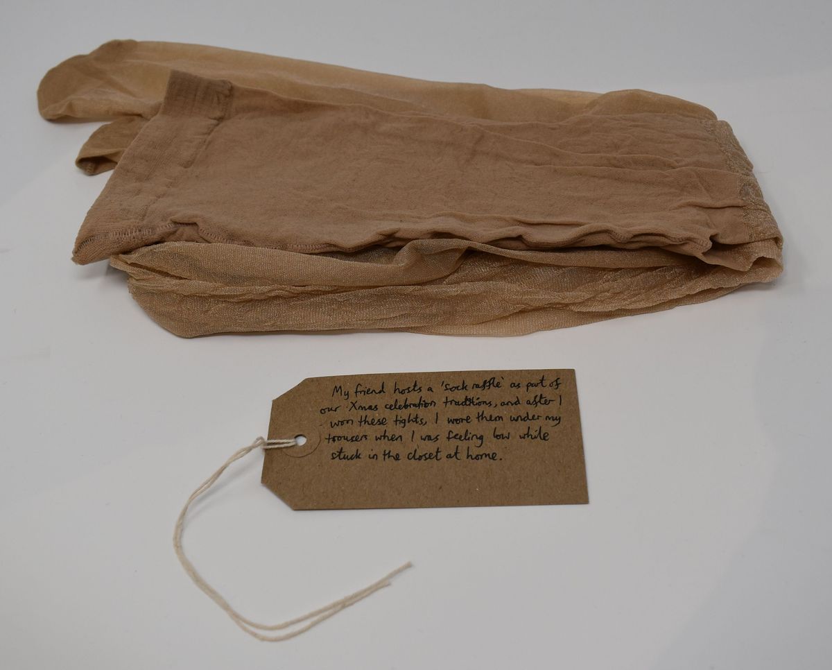 Pair of beige/natural tights with a brown handwritten luggage tag.