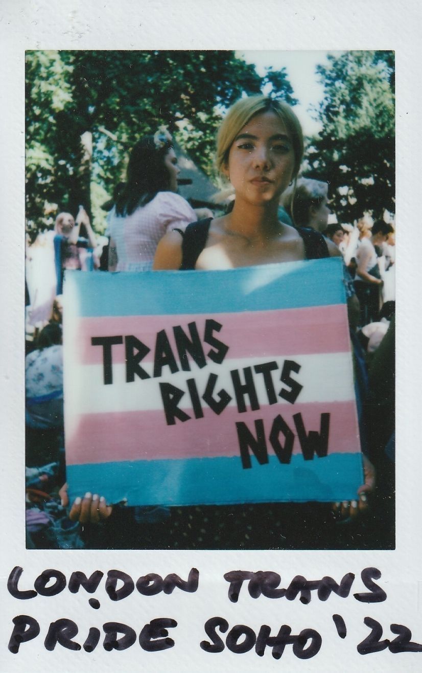 A person holds a "Trans Rights Now" sign at London Trans Pride in Soho, 2022.