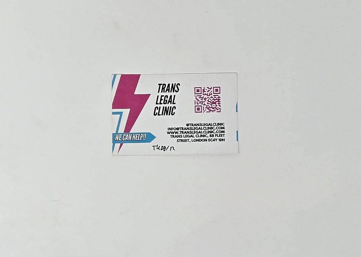 A white business card for the Trans Legal Clinic. There is a pink and blue lightning logo and a pink QR code, with contact details in black text.