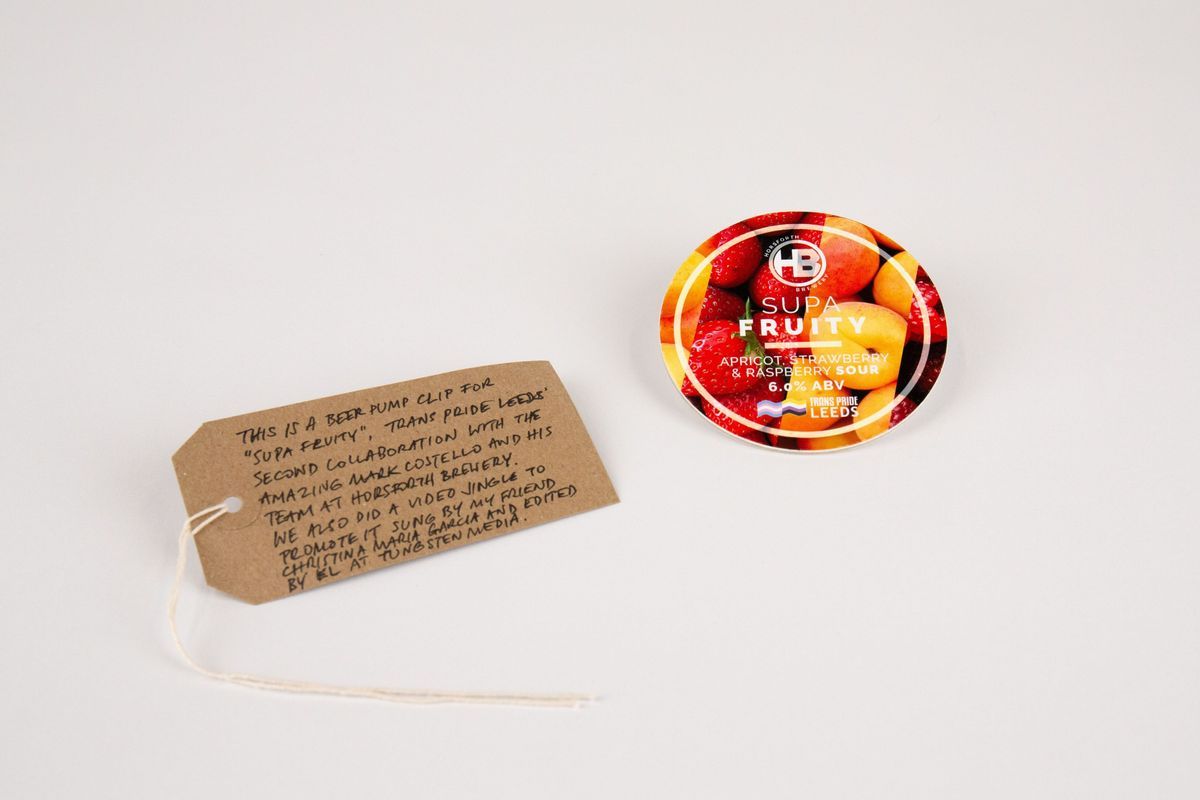 A beer pump clip for "Supa Fruity", brewed by Horsforth Brewery. The background shows apricots, strawberries and raspberries. With a brown, handwritten luggage tag.