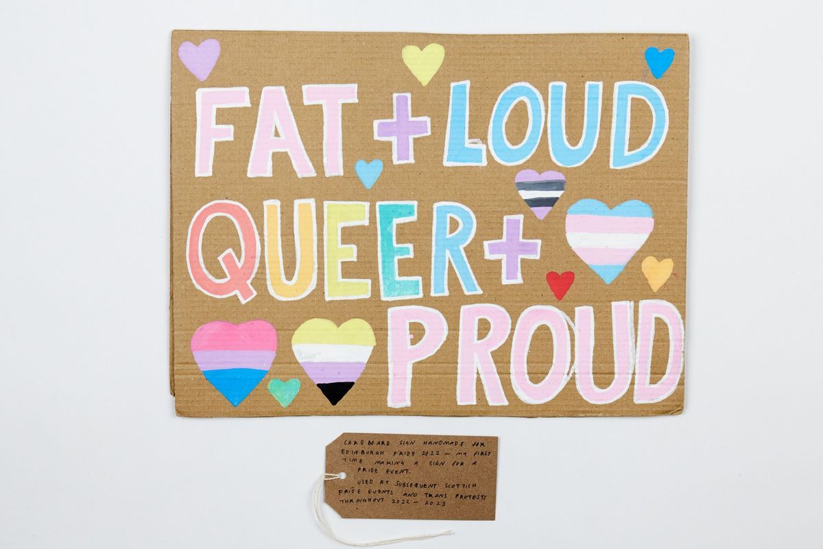 A placard which says Fat and loud, queer and proud in pastel colourful colours.