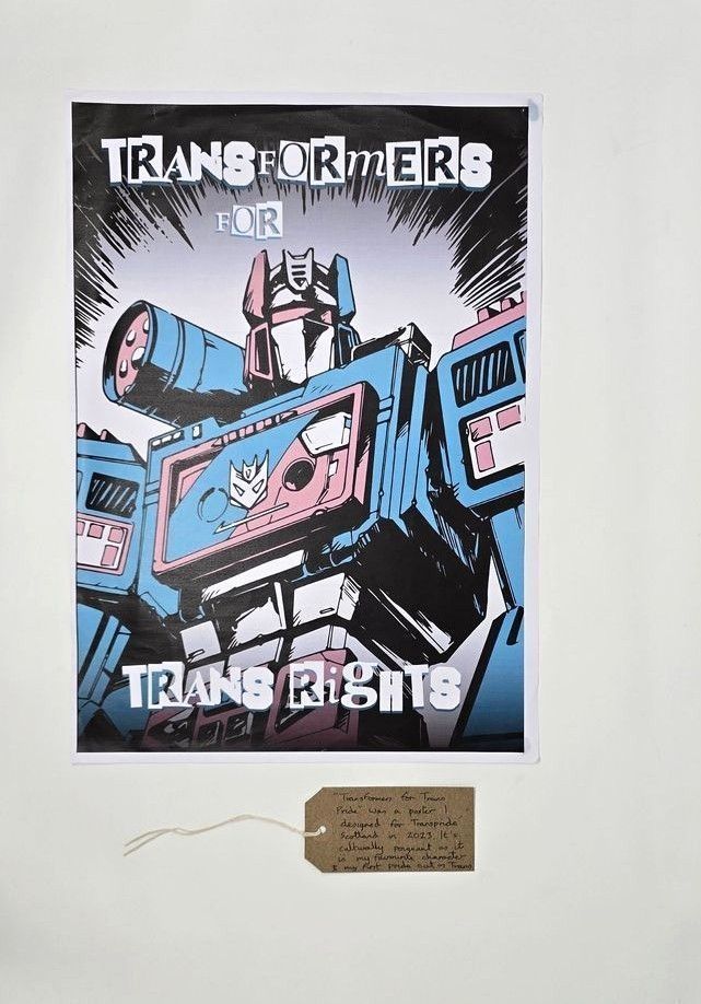A poster which says 'Transformers for Trans Rights' and has an illustration cartoon of a transformer but coloured in trans flag colours of pink, blue and white.