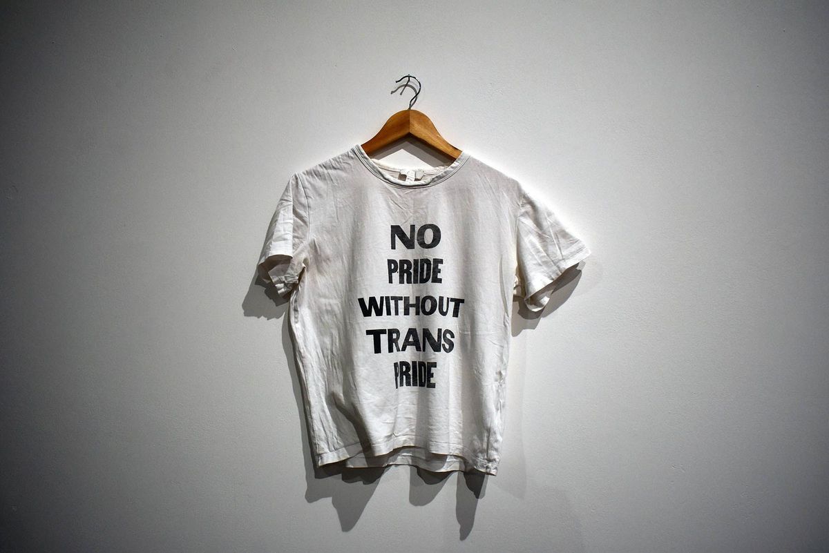 A white T-shirt on a hanger displays the message: "No pride without trans pride."