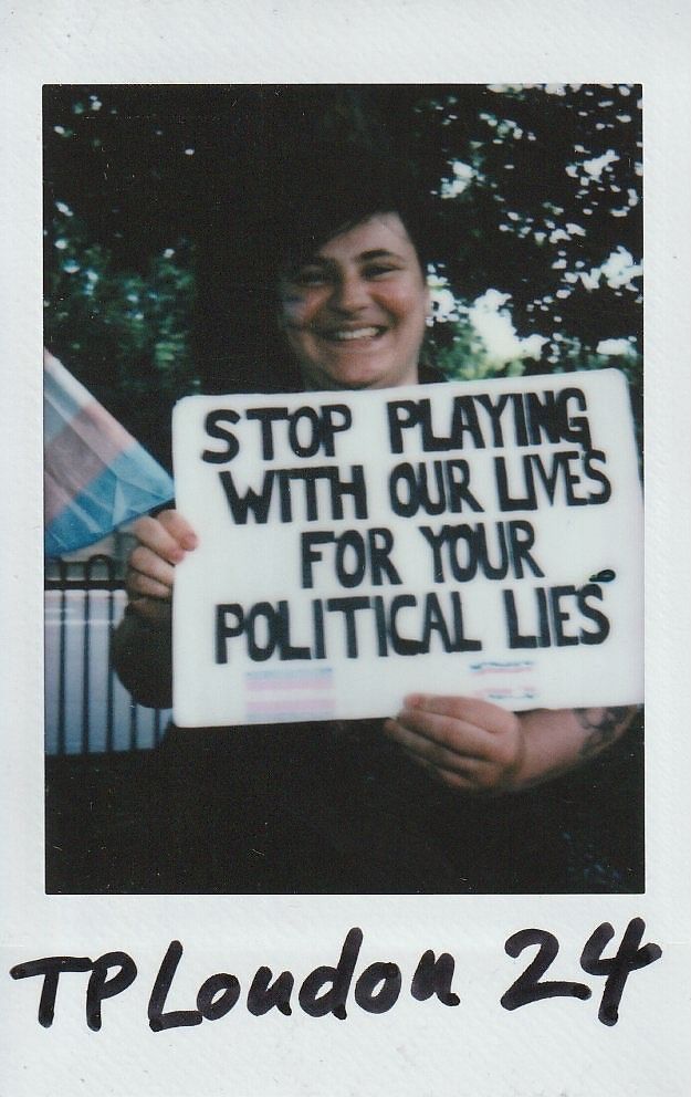 A person holds a sign saying, "STOP PLAYING WITH OUR LIVES FOR YOUR POLITICAL LIES".