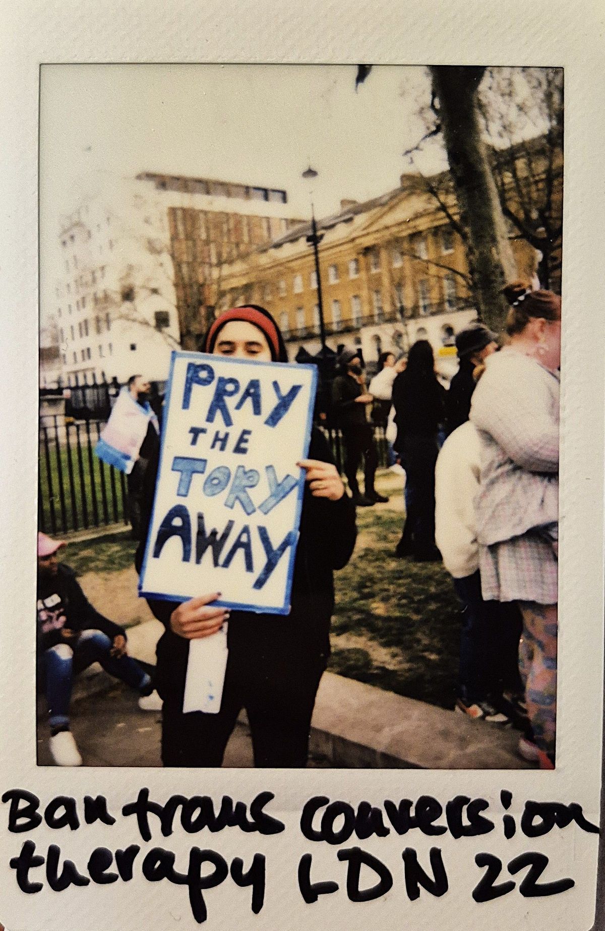 A person holds a sign reading "Pray the Tory Away" at a public protest gathering in London.