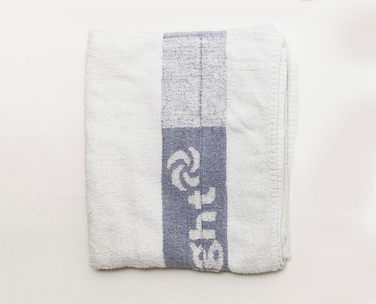 A neatly folded white towel features a distinctive blue stripe with a design and text.