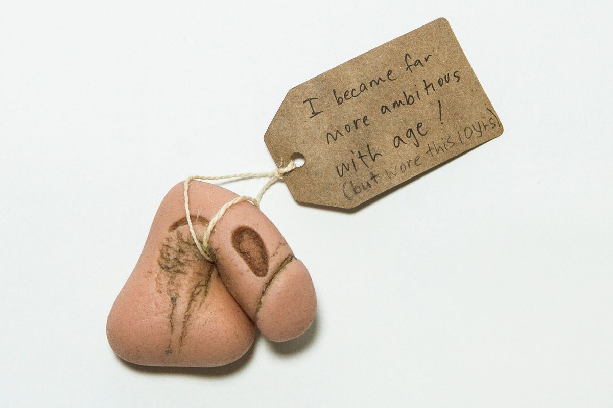 Prosthetic penis & testicles (packer) & tag; made of silicone, pink, moulded with grooves which have worn down & discoloured.