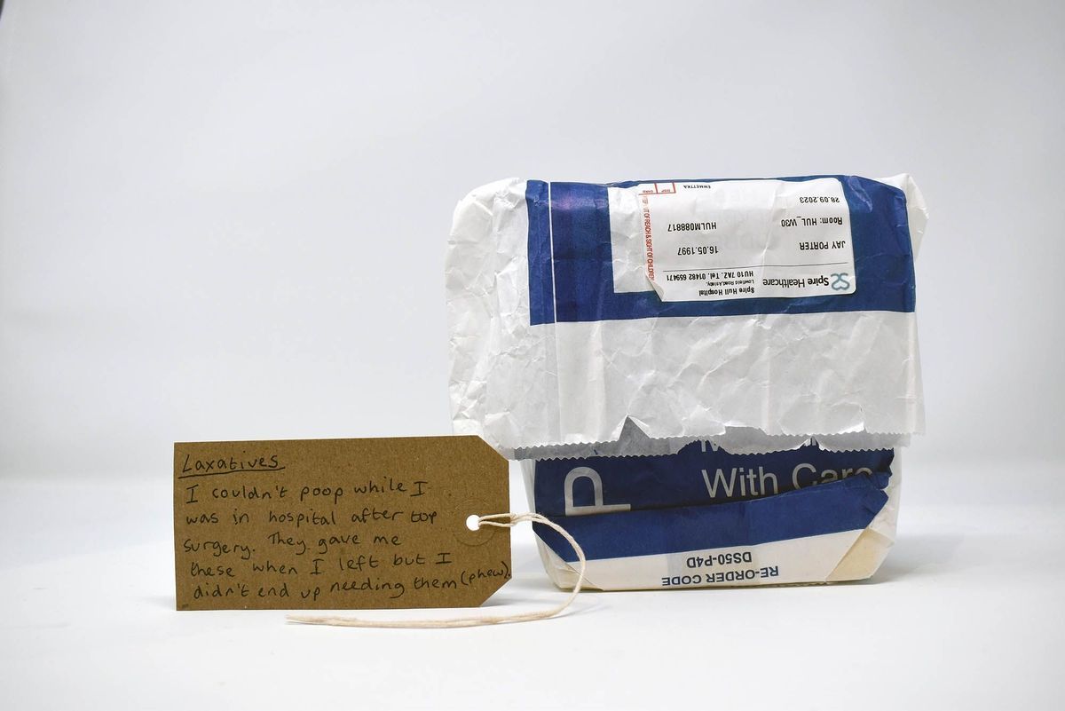A blue and white paper prescription bag, containing laxatives. With a brown, handwritten luggage tag.