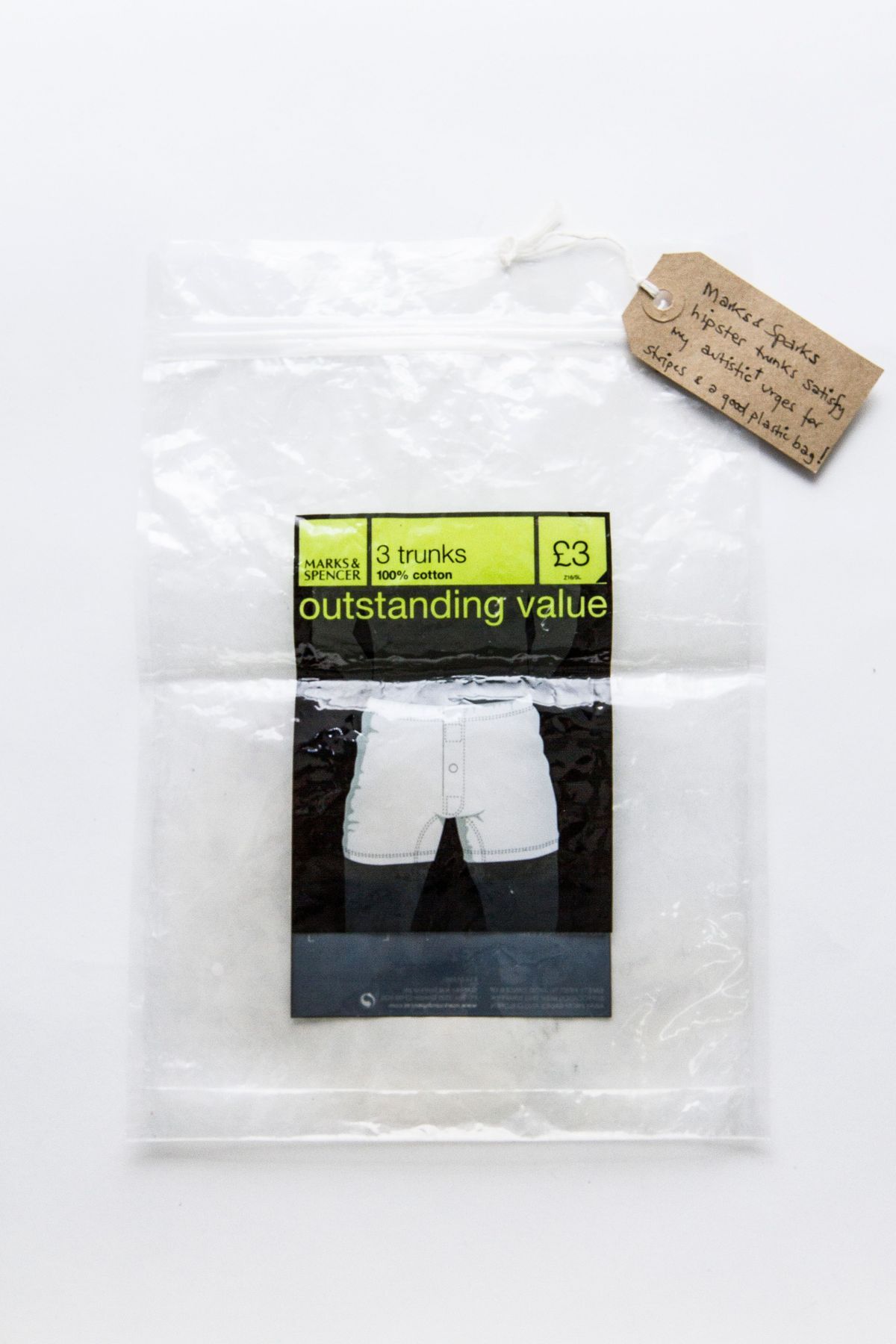 Plastic bag, packaging for M&S pack of 3 trunks. Rigid plastic, resealable bag, dark blue/green labelling. Surface covered in small dents. Several small circular magnets holding bag in folded in half position.