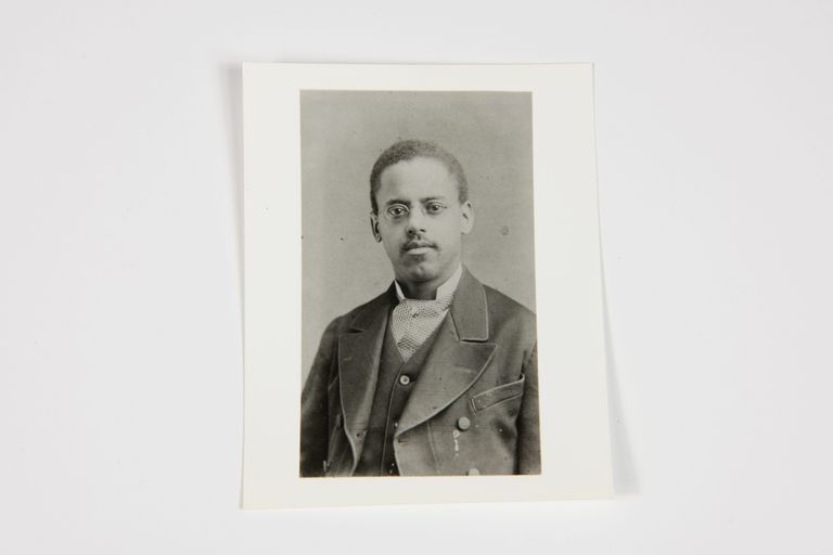 The image displays a formal portrait of Lewis Latimer in a suit, reflecting a historical setting.