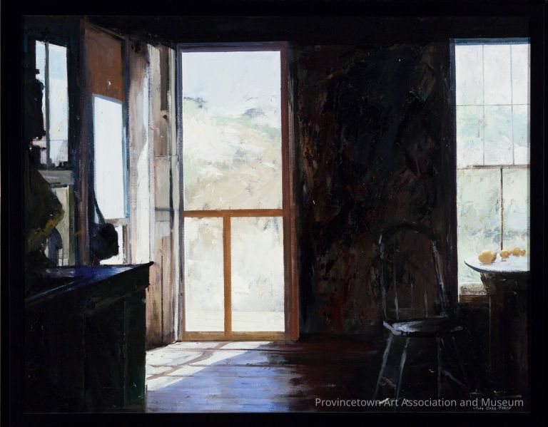 Interior scene of wooden dune shack with open door and light streaming in