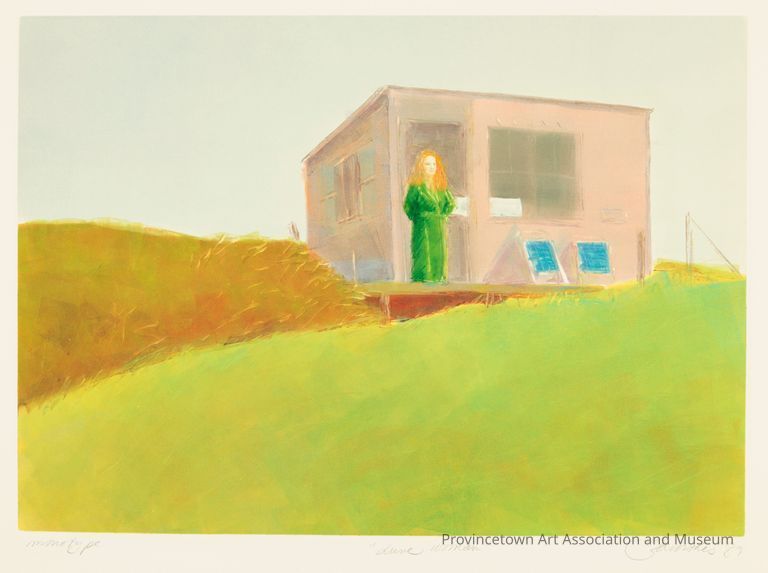 Woman wearing green standing on porch of brown dune shack