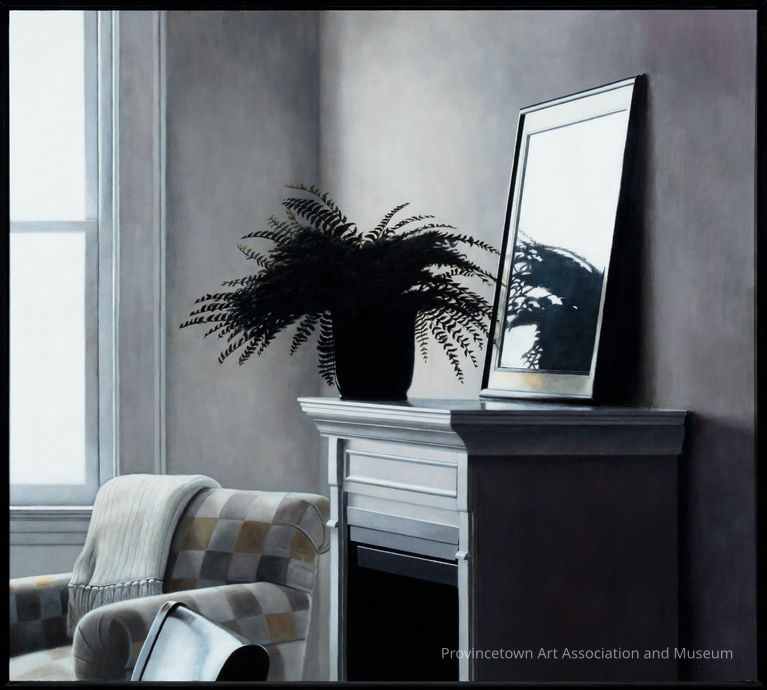 Interior with white walls; potted fern and mirror resting on a fireplace mantle, checkered armchair with folded blanket