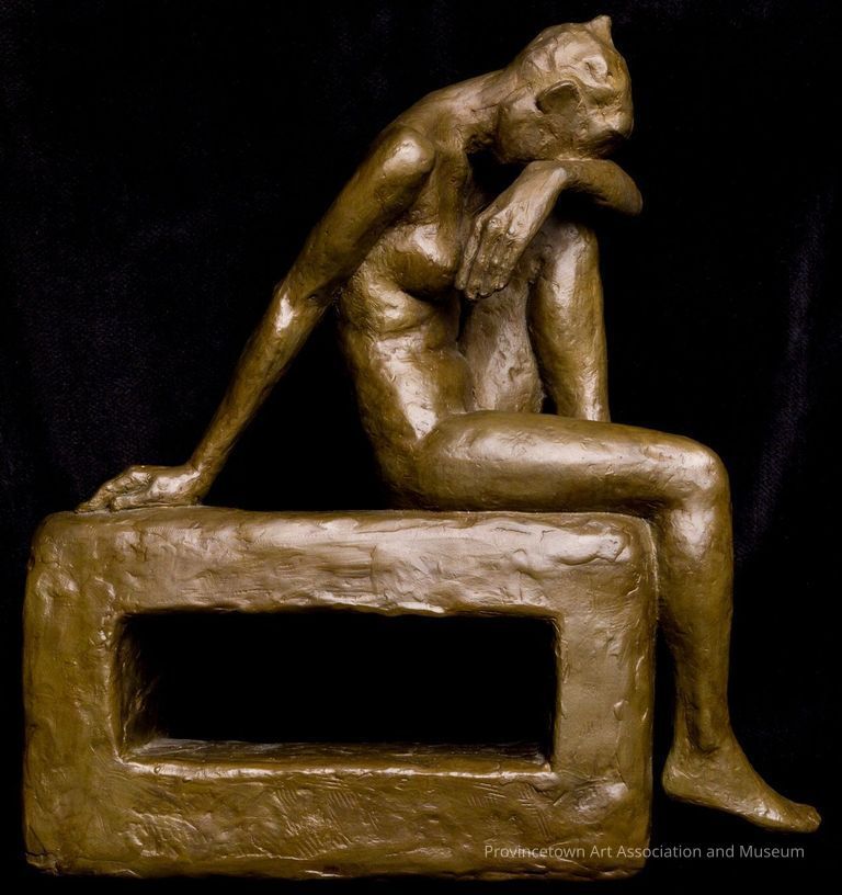 Woman sitting on block, with one knee up and head in her arms