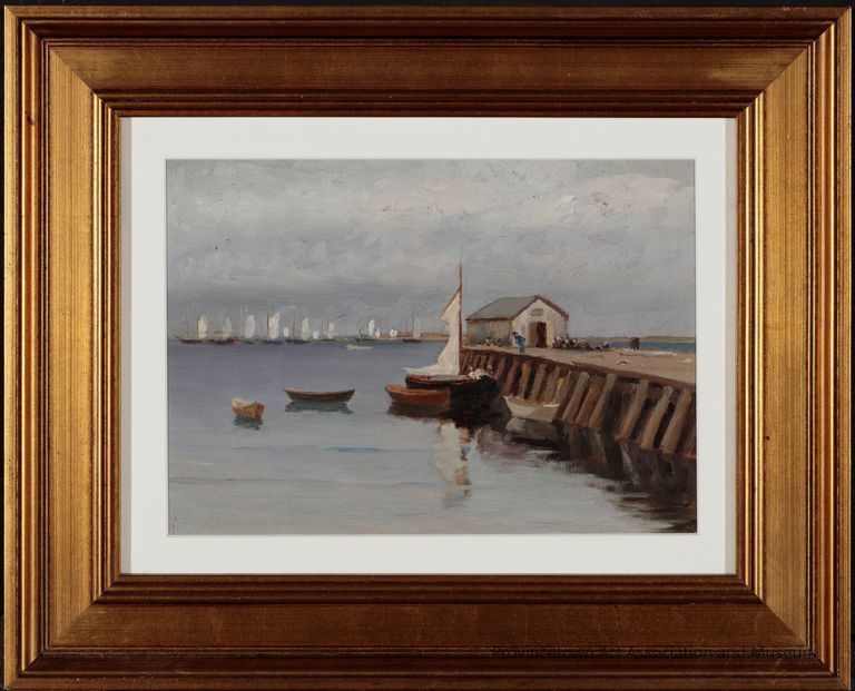 A pier extends into the water. At the end stands a fishing shack. Beside it five boats wait with their reflections cast on the water below. In the background, a fleet of white sailed boats are in view as they pass the distant beach with a cloudy sky above.