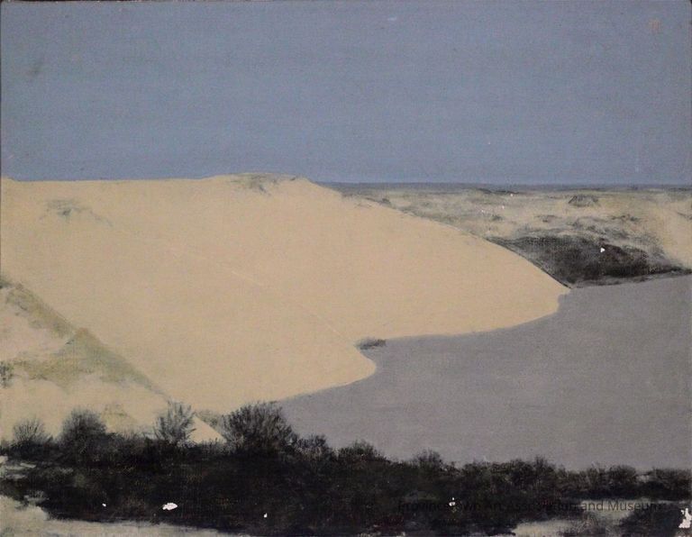 Sand dunes and gray body of water with blue sky background