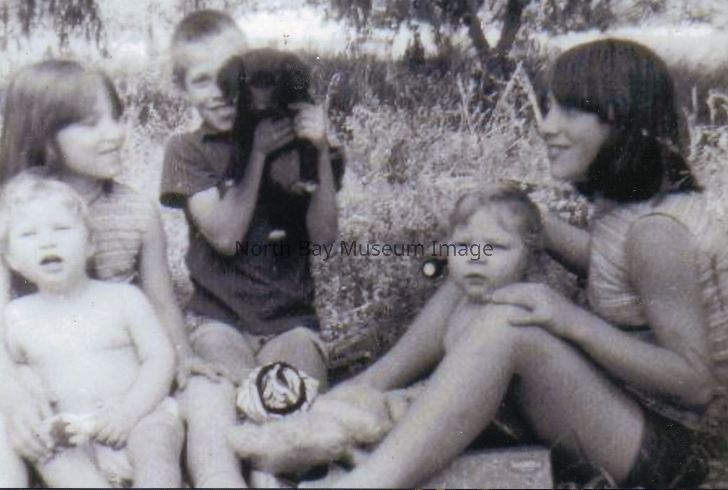 2025.01.014: A photo taken at the same time as 2025.01.011, this also shows several of the Rousseau children playing at a picnic in a heath. Two of the Triplets are present but I am unsure which. A black puppy is visible in David's hands. I have seen no mention of the family owning any other pets besides cats Smoky and Fluffy. The dog therefore may be the property of the girl to the far left who seems to be a friend or relative.