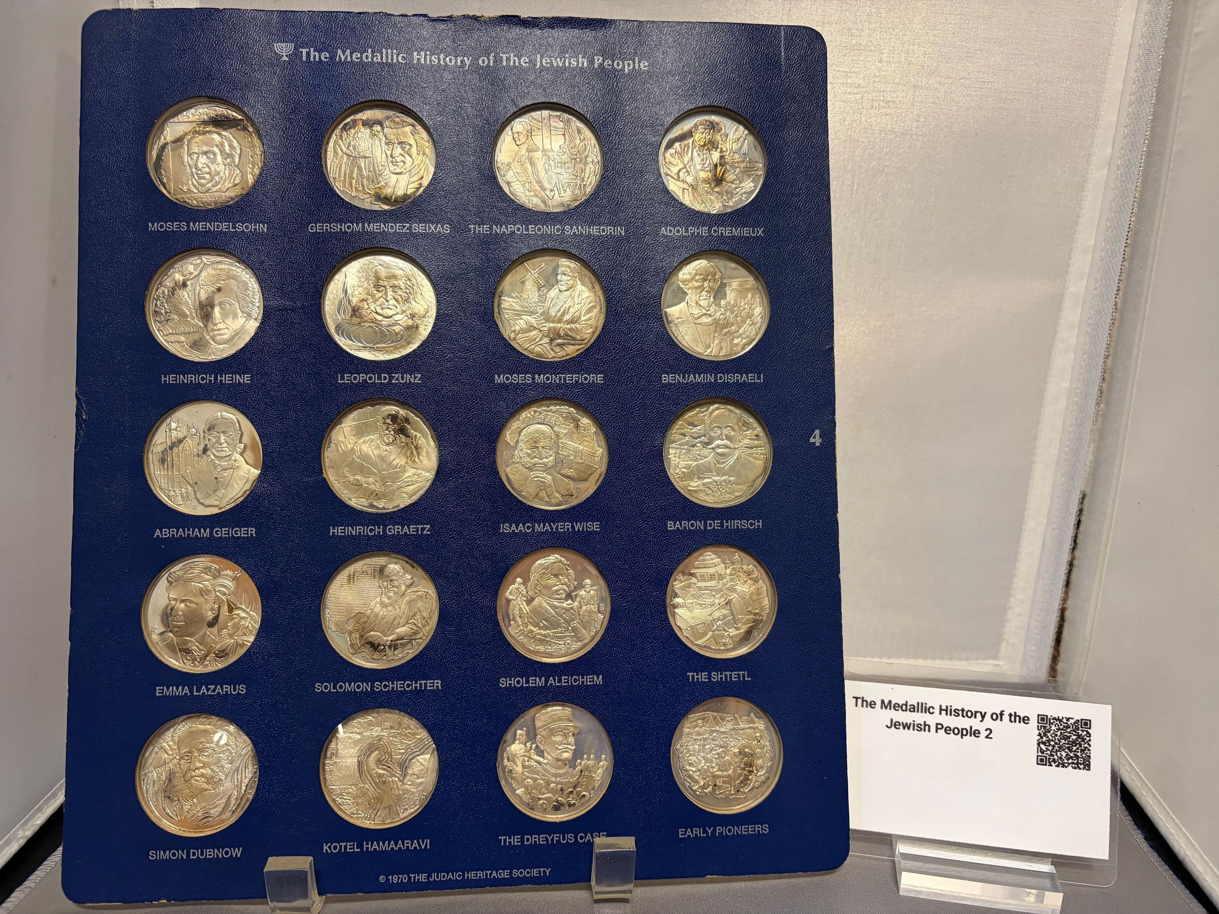 History of the Jewish People (4): The image displays an arrangement titled "The Medallic History of the Jewish People," featuring a collection of sixteen detailed medallions, each representing significant figures, events, and themes in Jewish history. Each medallion bears an inscription with names or iconic phrases such as "Jewish Defense," "Hannah Szenes," "Albert Einstein," and "Exodus," showcasing both influential individuals and pivotal moments.