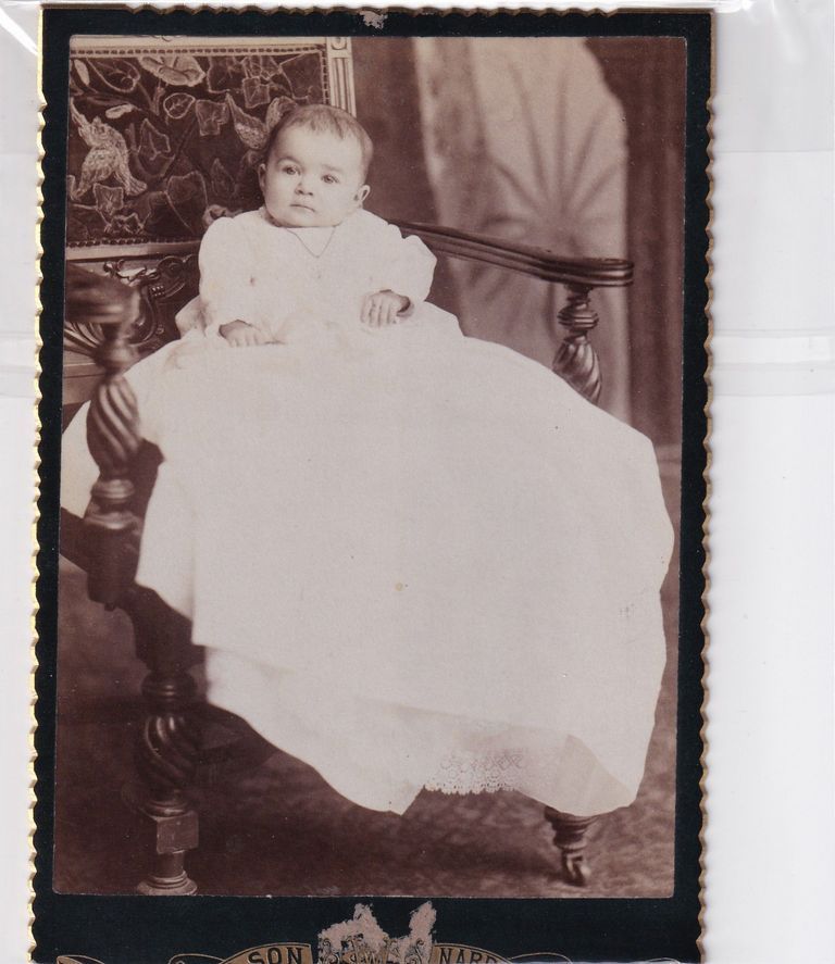 Infant in Long Christening Gown Seated on Ornate Bench — Studio Portrait