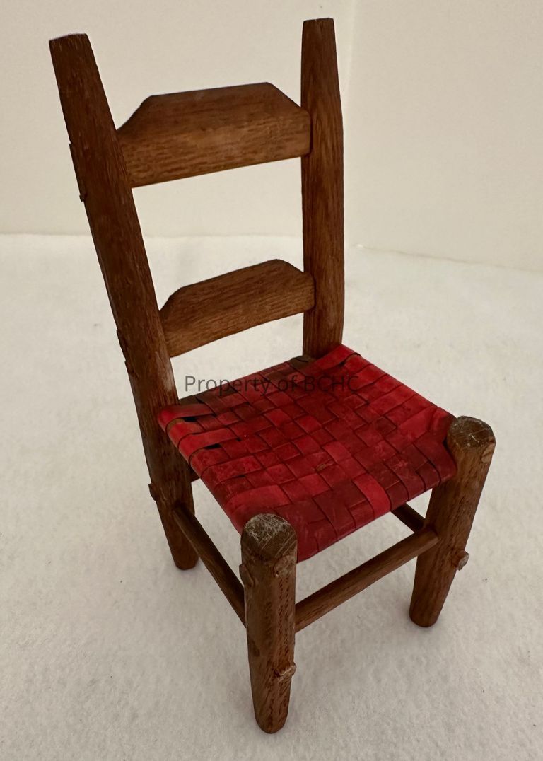 Wooden chair, with red, caned seat.