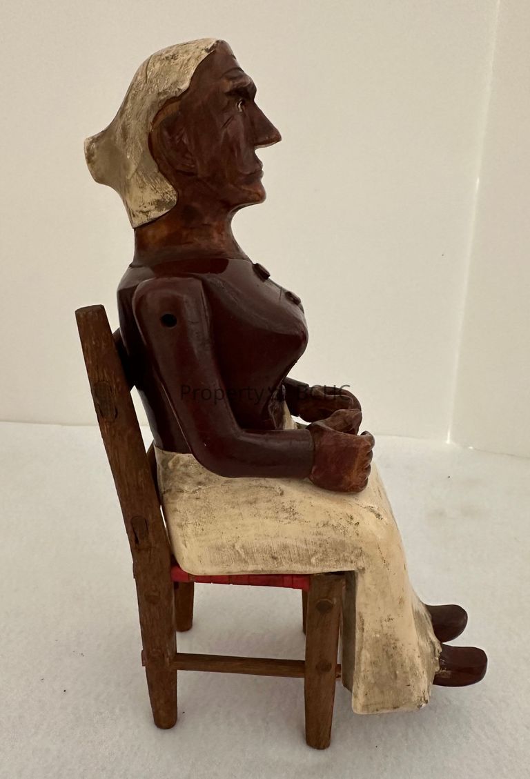 Carving of woman sitting in a chair (2 pieces) at a spinning wheel.
