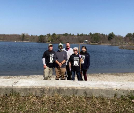 SLHS sponsored "Town Beach Team" during the Spring 2021, TOSL Earth Day Event: SLHS sponsored "Town Beach Team" during the Spring 2021, "Make Sand Lake Shine," Earth Day celebration, town-wide clean-up. SLHS volunteered to clean-up the Town Beach area. Pictured are Jane Minotti, Jennifer Perry and Mike Perry of SLHS plus additional volunteers Jesse Keltz and Kevin Williams. The Team collected and removed numerous bags of litter, debris and leaves from the Town Beach area. SLHS participants wore, "Who Killed Hazel Drew," t-shirts, which helped attract several new SLHS members as well as sell three t-shirts.