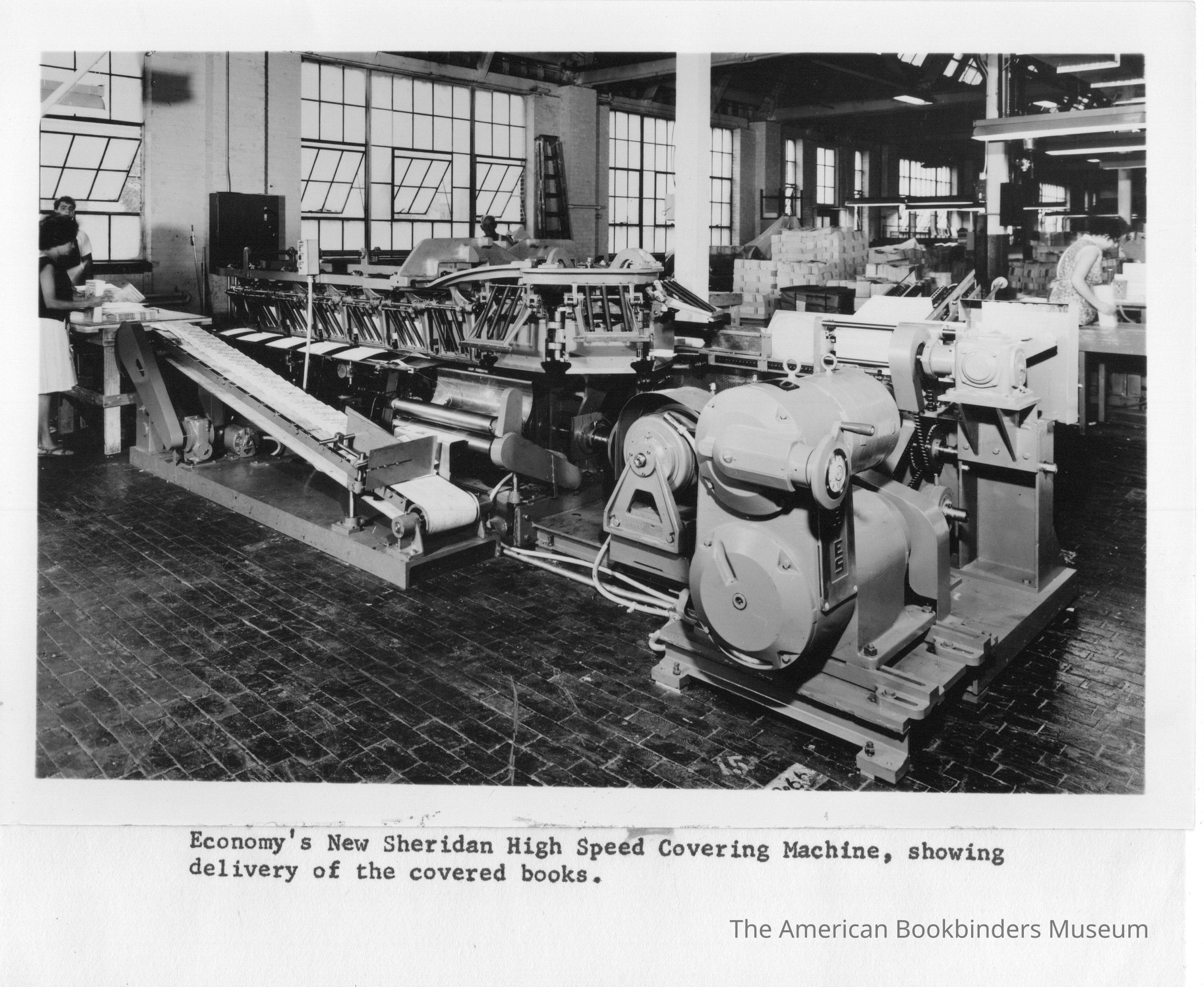 This shows a Juengst style covering machine manufactured by Sheridan at their Easton, PA plant and shipped to Economy who was a trade binder in Hoboken, NJ. The machine was installed in July of 1963. I cataloged this because early photos of binding lines in production were hard to locate. The line depicted collated signatures and applied a cover and was piled down by hand before being fed into a trimmer.