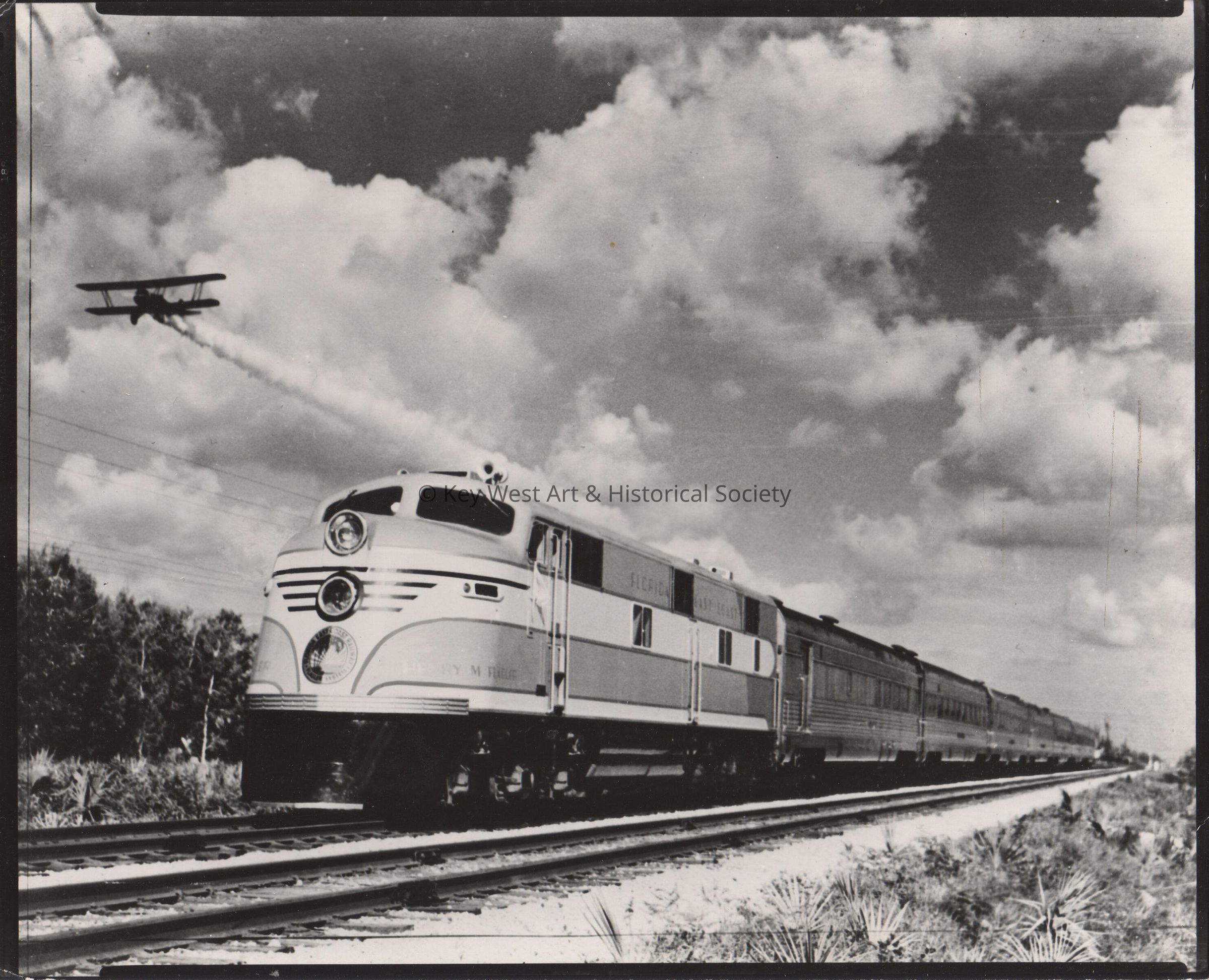 An airplane flying near a Florida East Coast train picture number 1