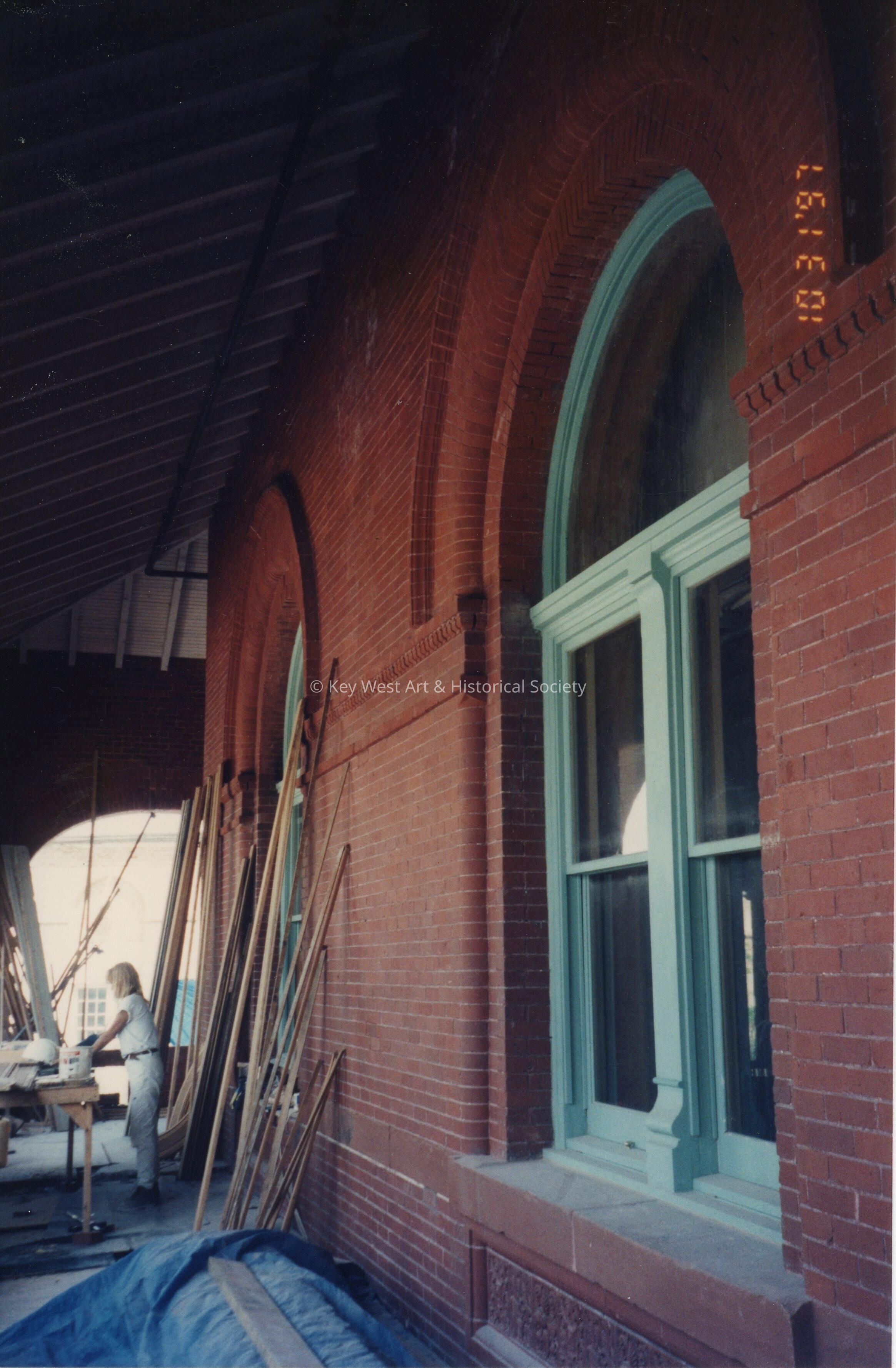 An unknown woman doing some work at a work table on the porch.
