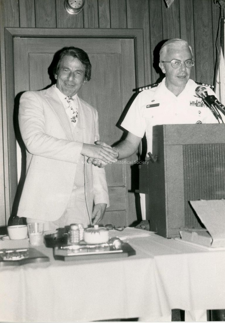 2 Unknown men shaking hands standing behind a podium