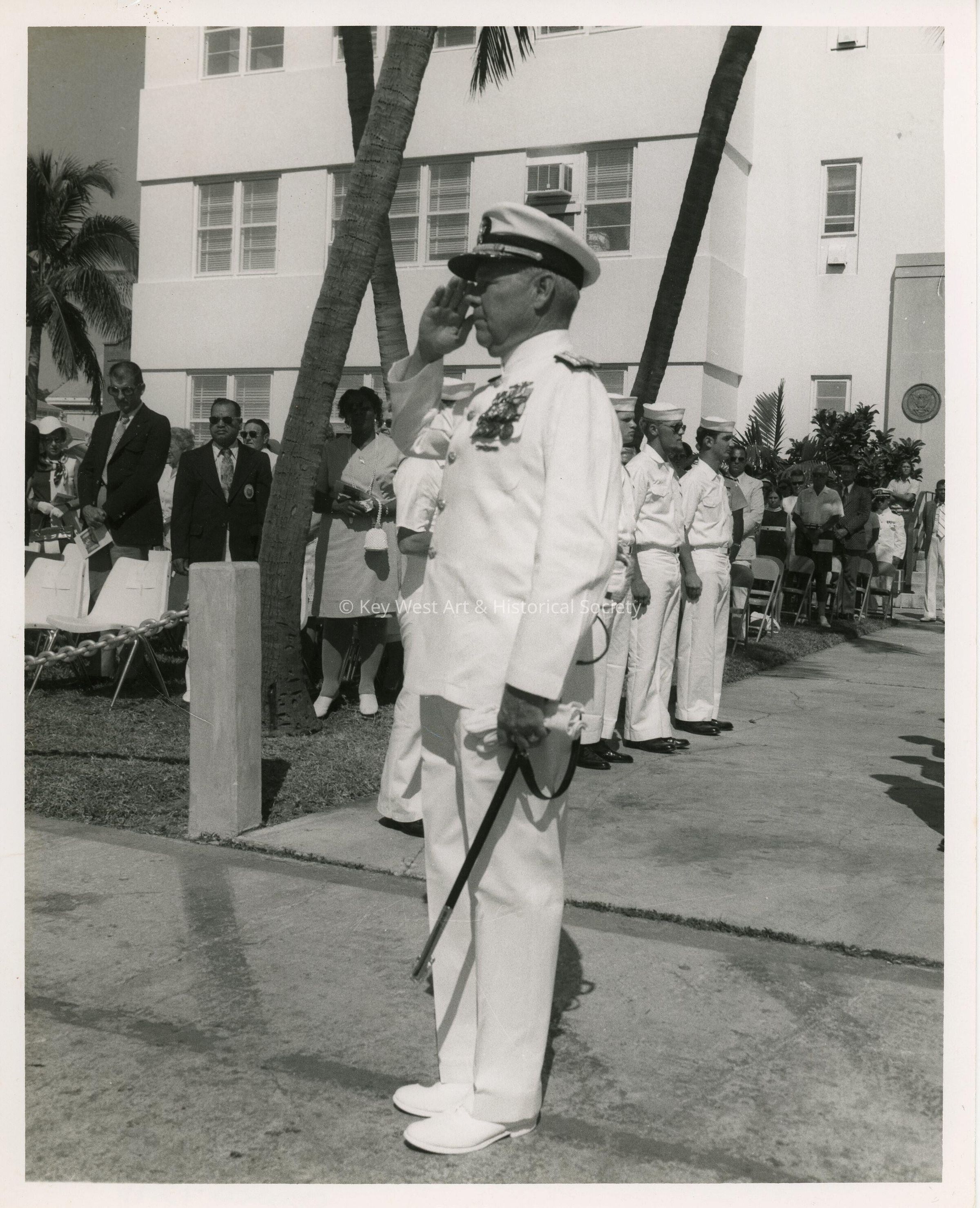 An unknown man saluting with a group in the back ground