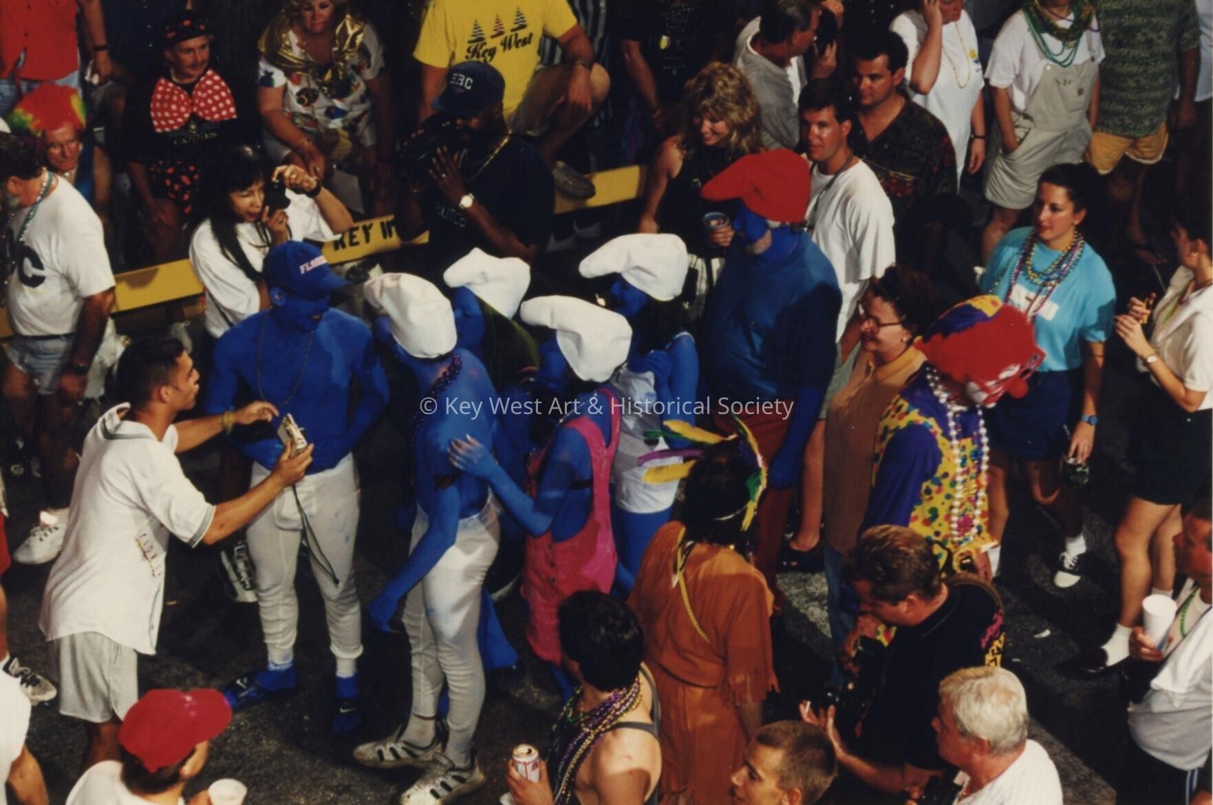 A group of unknown people dressed up walking in the street.