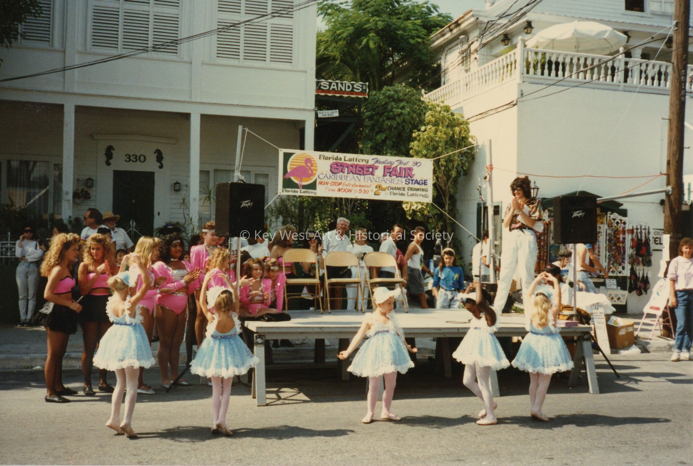 A group of unknown kids dancing in front of a stage.