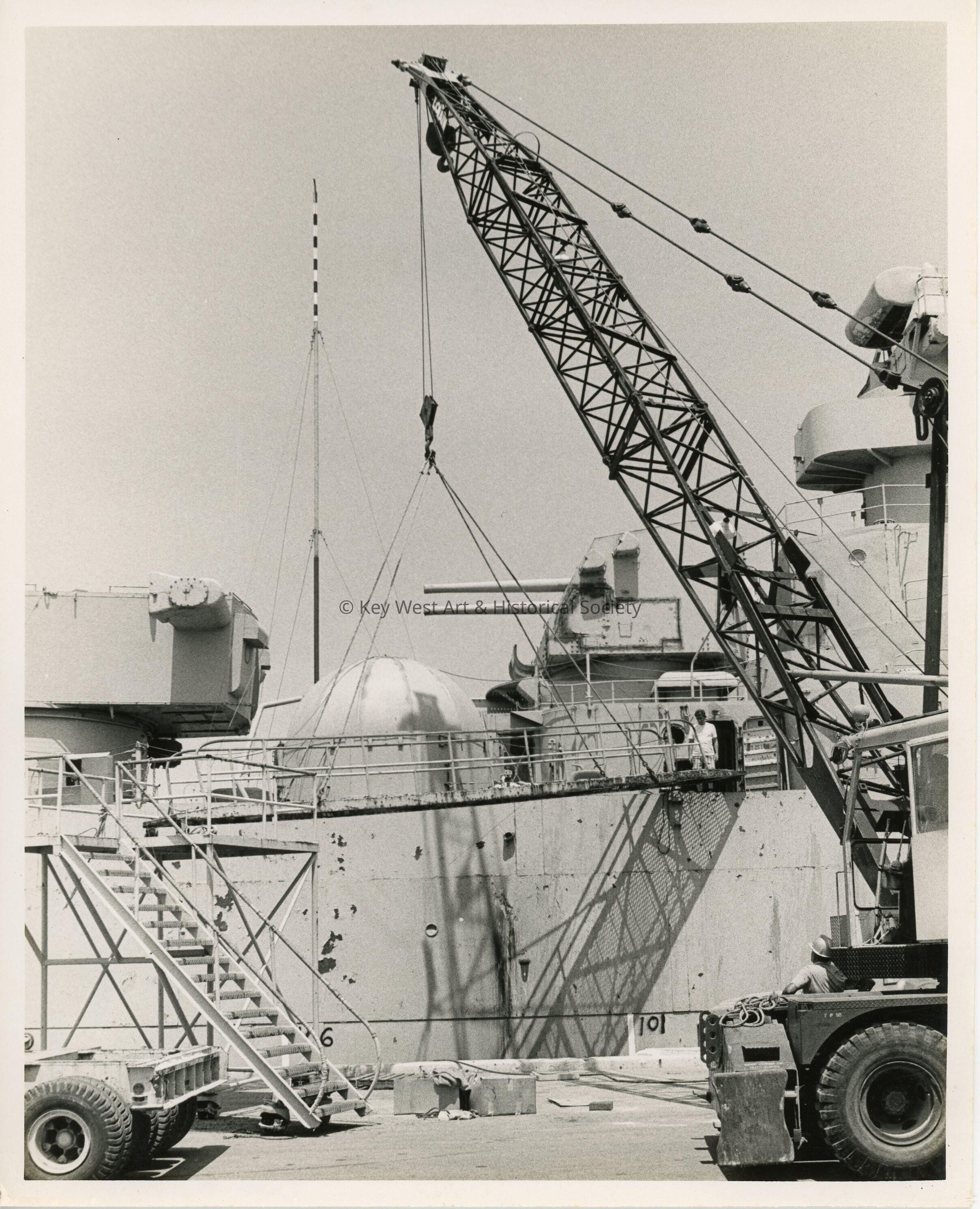 A crane lifting things into a ship