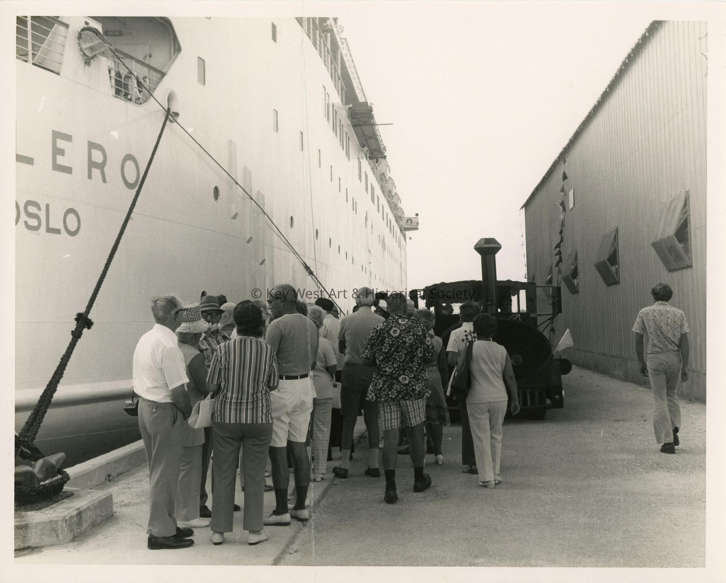 A group of knknown people on the pier in between 2 Navy ships