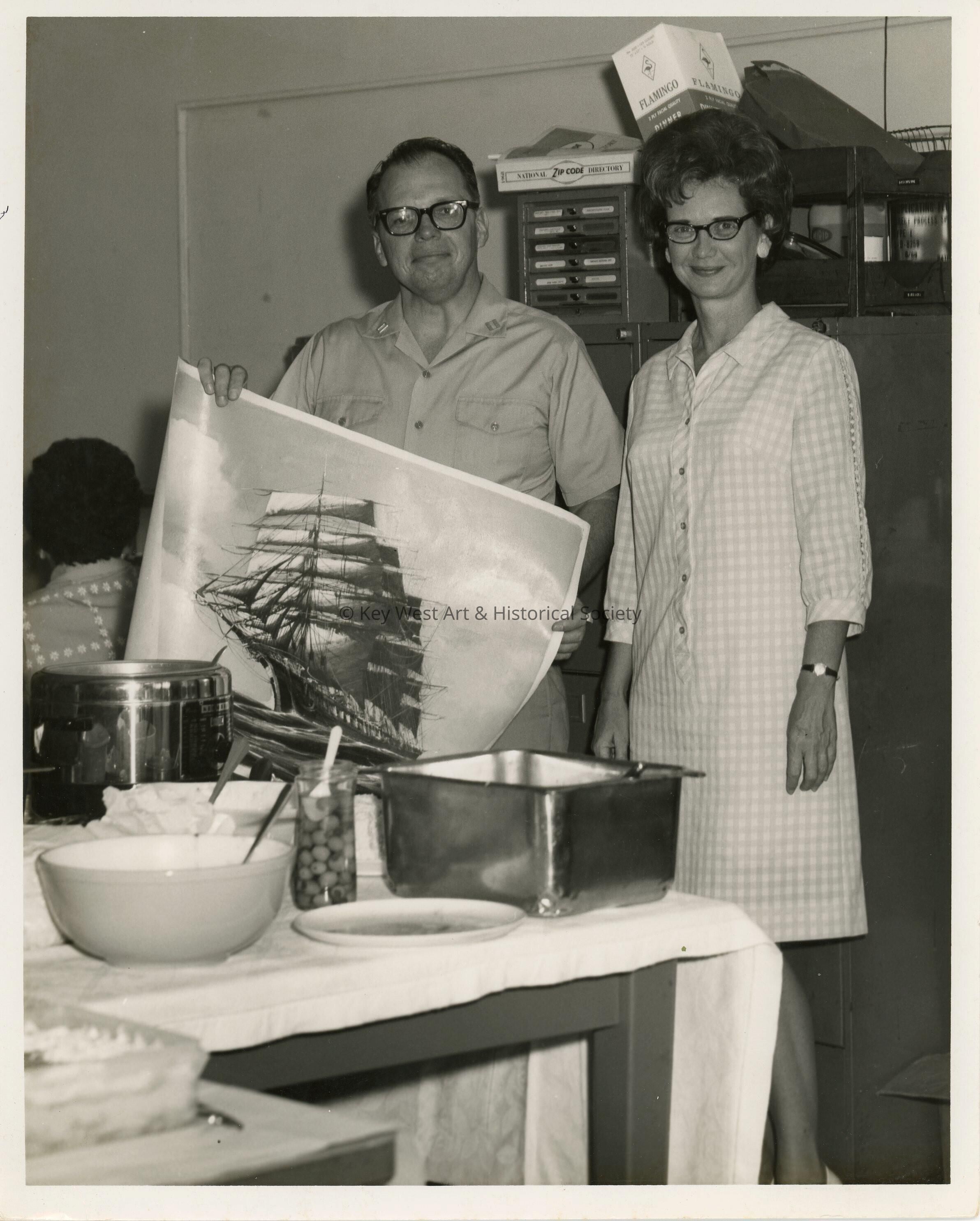 An unknown lady and man holding up artwork at a party