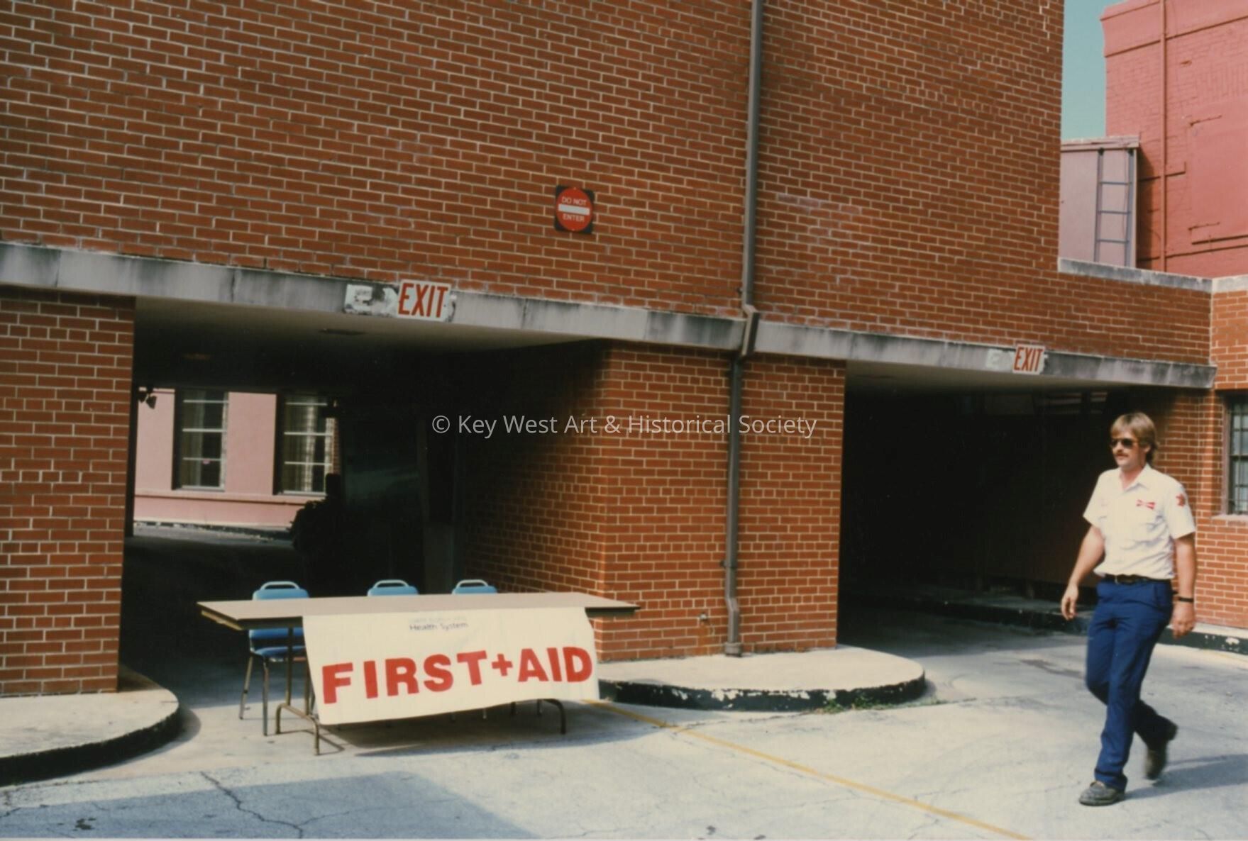 A brick unknown building with a first aid table set up.