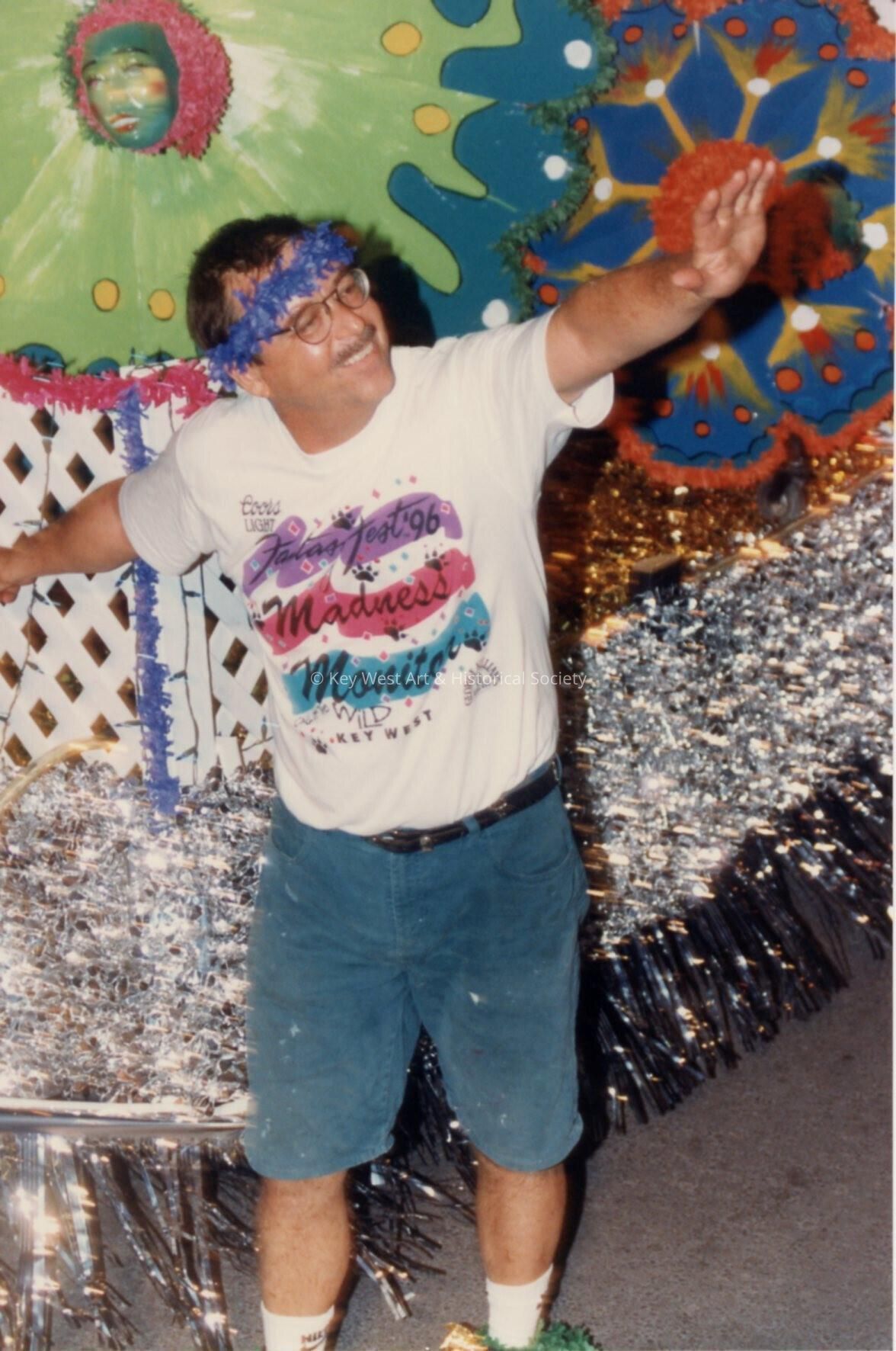A Fantasy Fest parade monitor standing next to a float.