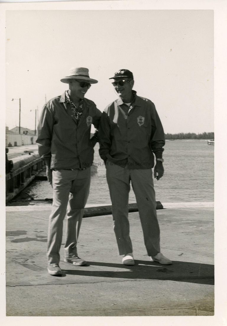 2 Unknown men standing near a pier